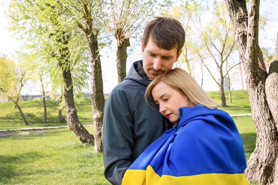 Happy Ukrainian couple holding hands and hugging against background of national Ukrainian symbols